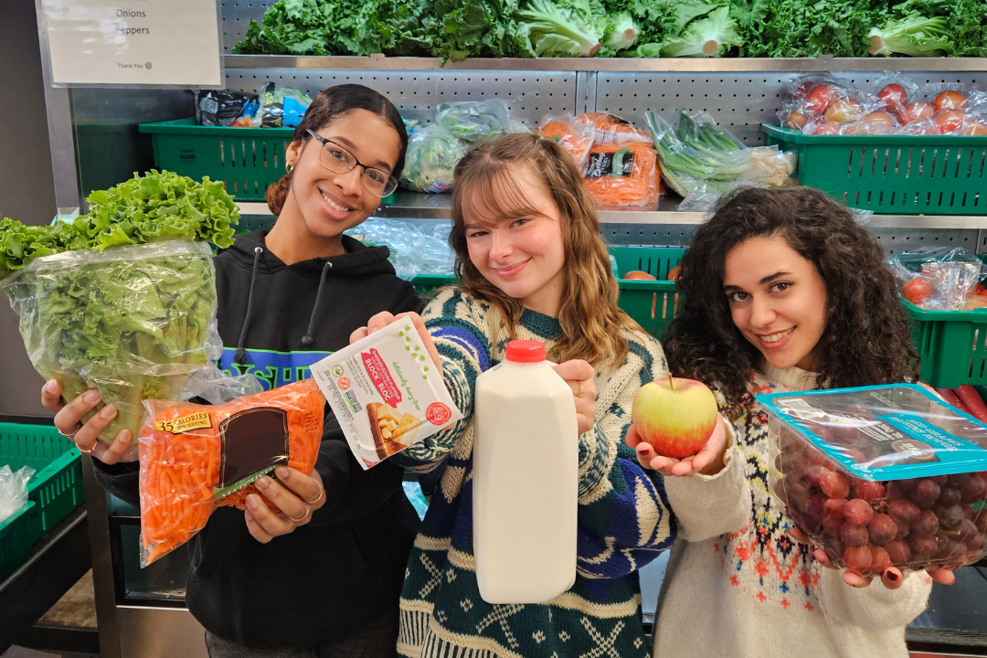 Three girls holding food items, posing for a picture