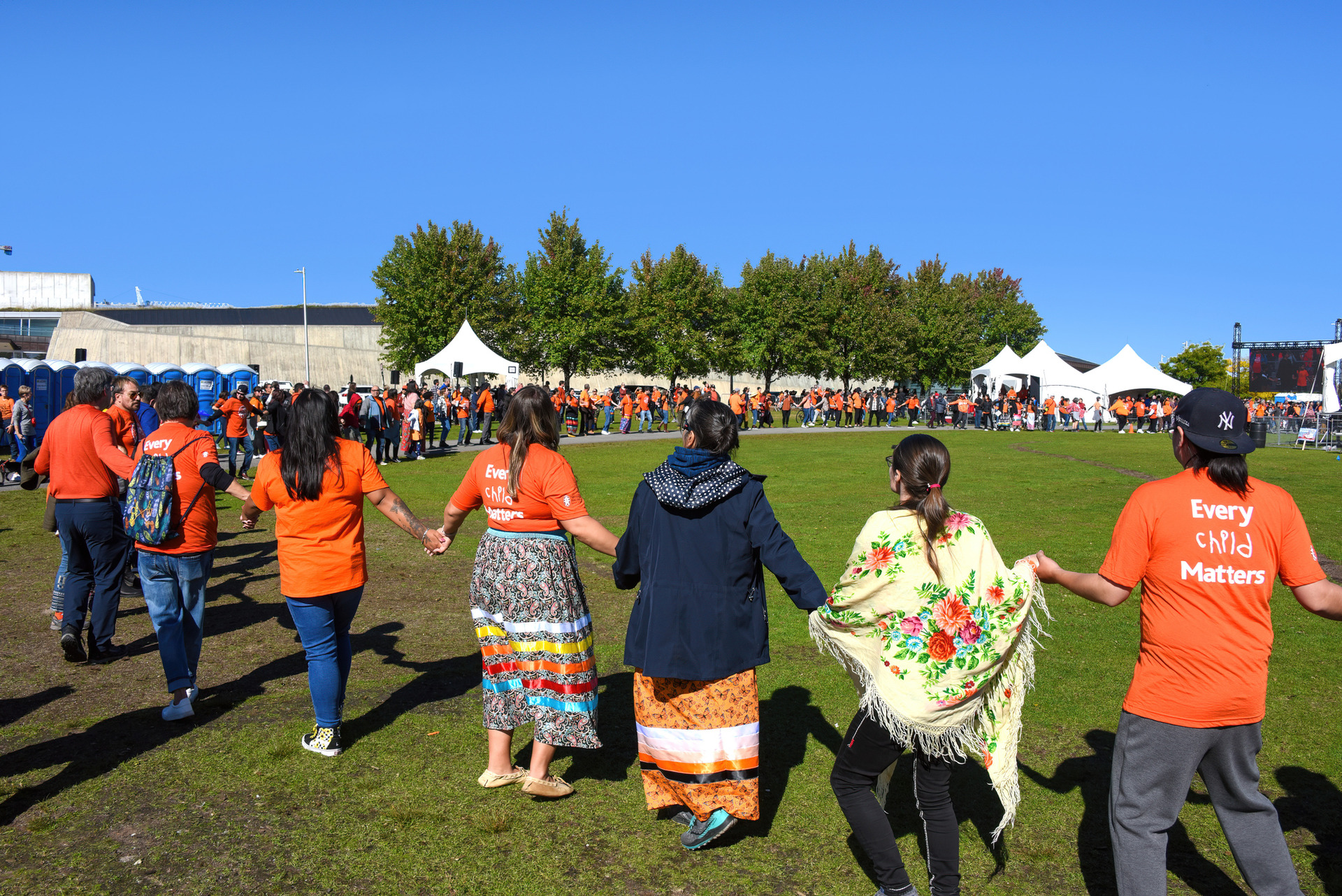 group of people holding hands in a circle, wearing orange shirts for NDTR