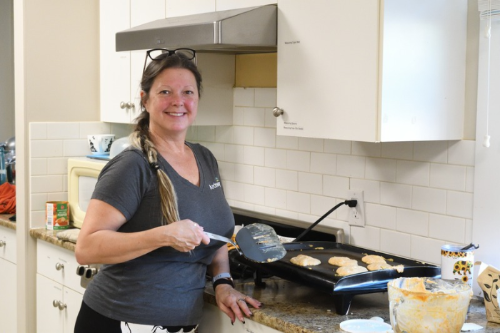 A lady holding a spatula making pancakes 
